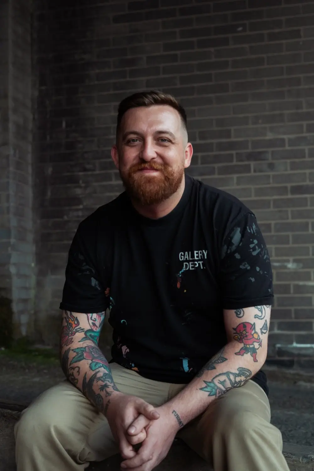 Portrait of Vinny Rowan seated against a brick wall