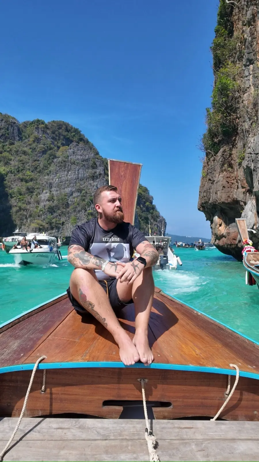 Vinny seated on the bow of a longtail boat between limestone cliffs in Thailand